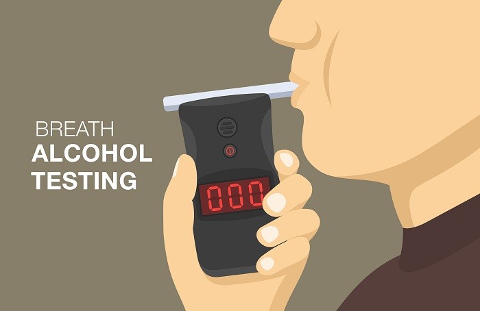 「BREATH ALCOHOL TESTING」という文字の横で、人物が携帯型のアルコール検知器を手に持ち、呼気検査をしている様子のイラスト