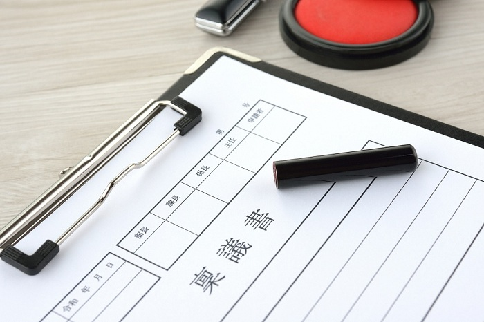 稟議書が挟まれたバインダーと印鑑と朱肉